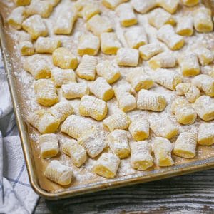 Homemade potato gnocchi floured and uncooked on a sheet pan.