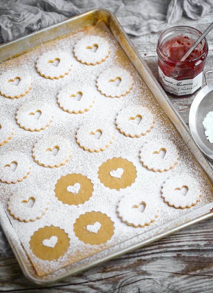 The top cookie of linzer cookies dusted with powdered sugar.
